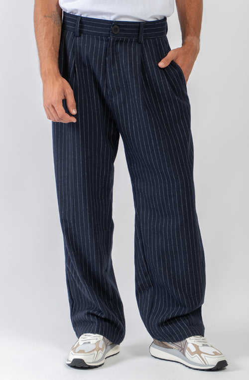 Pantalón Belle Époque navy de raya diplomática blanca con pinzas delanteras, pernera ancha y detalle Kaotiko Society trasero.