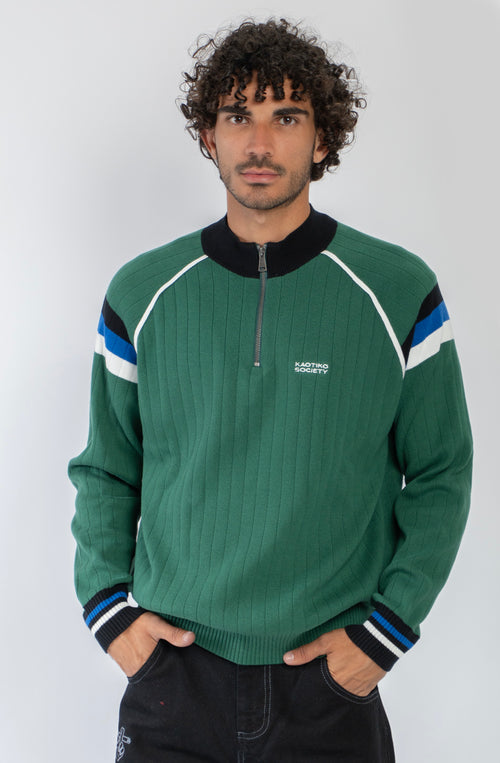 Jersey de punto verde con media cremallera, cuello alto y detalles deportivos en blanco, negro y azul.
