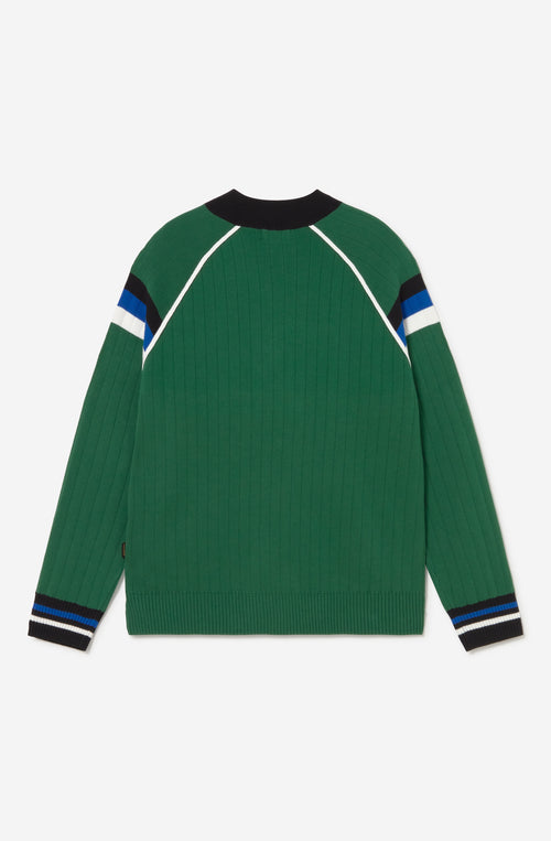 Jersey de punto verde con media cremallera, cuello alto y detalles deportivos en blanco, negro y azul.