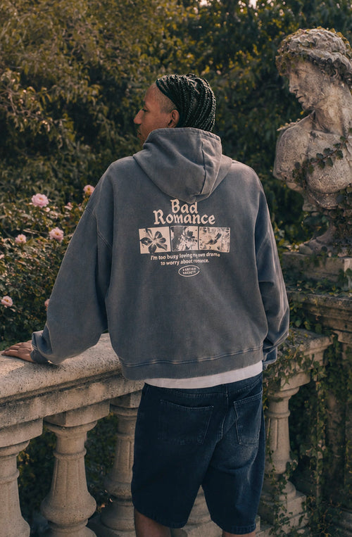 Sudadera oversize gris oscuro con acabado washed, capucha, bolsillo canguro y gráficos Bad Romance de Kaotiko Society.