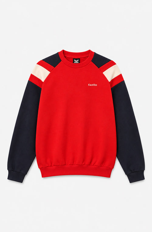 Sudadera unisex Rocco roja con mangas azul marino, franjas crudas en los hombros, cuello redondo y logo Kaotiko en el pecho.
