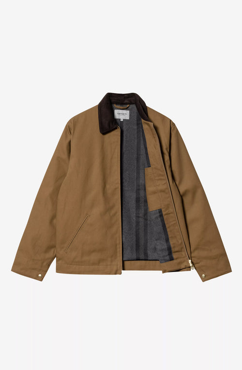 Chaqueta Carhartt WIP color Hamilton Brown con cuello de pana marrón oscuro, cierre de cremallera y bolsillos frontales.