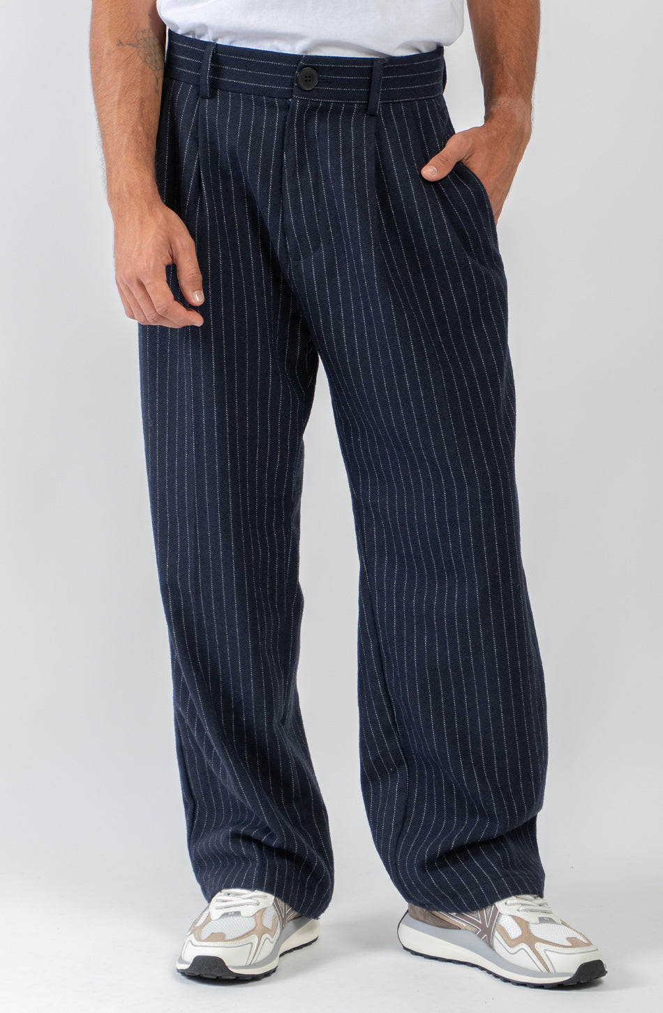 Pantalón Belle Époque navy de raya diplomática blanca con pinzas delanteras, pernera ancha y detalle Kaotiko Society trasero.