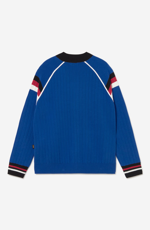 Chaqueta de punto azul con cremallera, cuello bomber y detalles deportivos en blanco, negro y rojo.