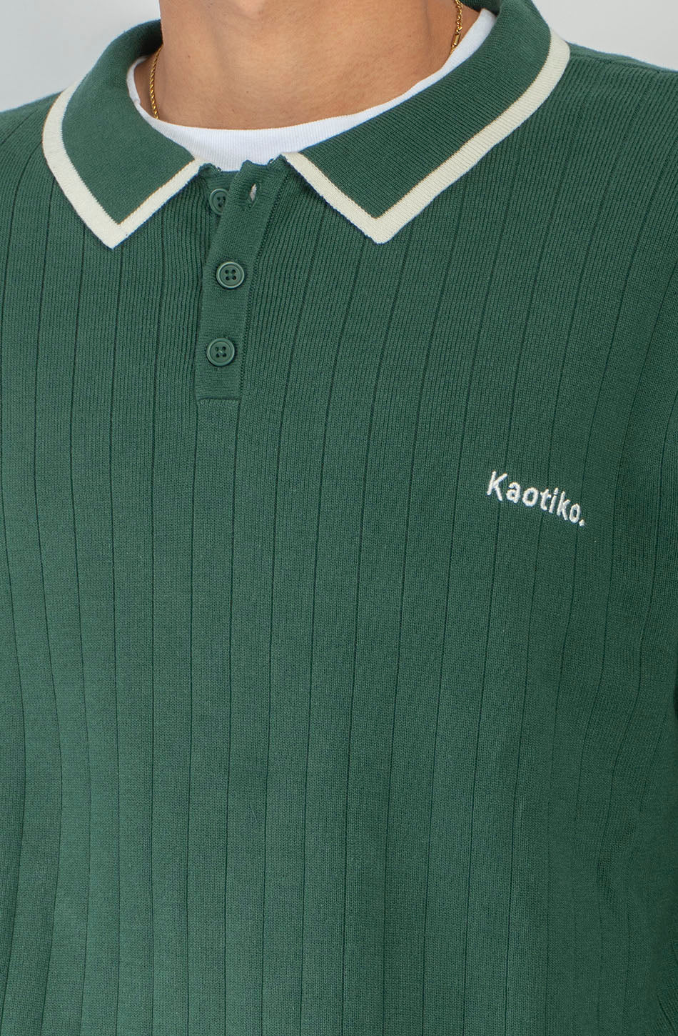 Polo unisex de punto verde de canalé con cuello de botones, detalles en contraste color crudo y bordado Kaotiko en el pecho.