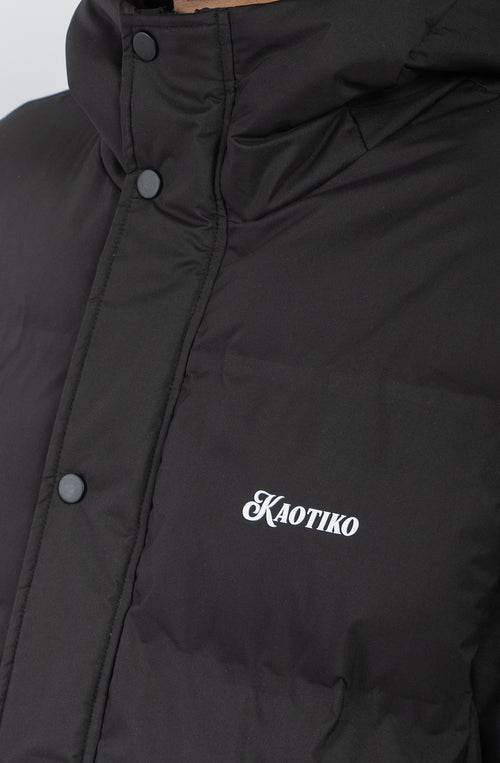 Chaqueta acolchada azul marino oscuro con capucha, cierre frontal y logo Kaotiko bordado en el pecho.