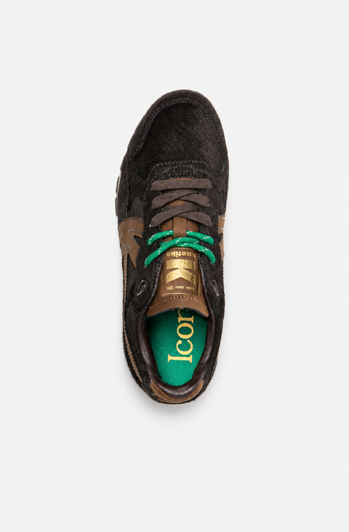 Zapatillas Seattle Pony Brown con acabado de pelo marrón oscuro, logo lateral marrón, cordones verdes y mediasuela en tono crudo.