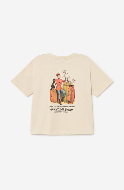 Camiseta relaxed fit de algodón orgánico color ivory con logo Hotel Belle Époque en el pecho y gran ilustración vintage de un botones con perros y equipaje en la espalda.